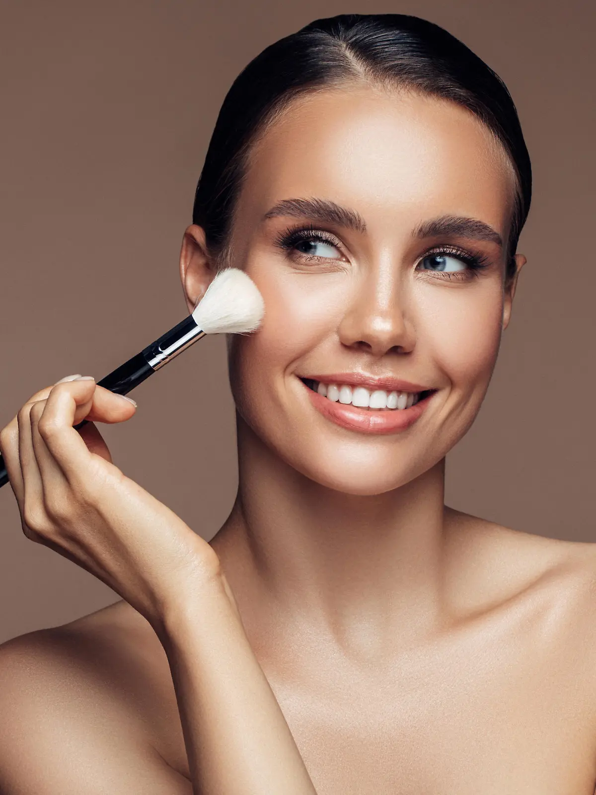 Beautiful young woman applying foundation powder