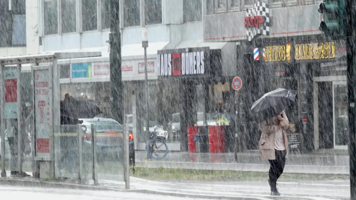 26.07.2023, Nordrhein-Westfalen, Düsseldorf: Eine Frau läuft im Regen durch die Düsseldorfer Innenstadt. Nach zuletzt durchwachsenem und oft grauem Wetter in Nordrhein-Westfalen geht es auch in den nächsten Tagen eher herbstlich als hochsommerlich weiter. (zu dpa «Herbstliches Wetter mitten im Hochsommer in NRW») Foto: Linda Henrich/dpa +++ dpa-Bildfunk +++