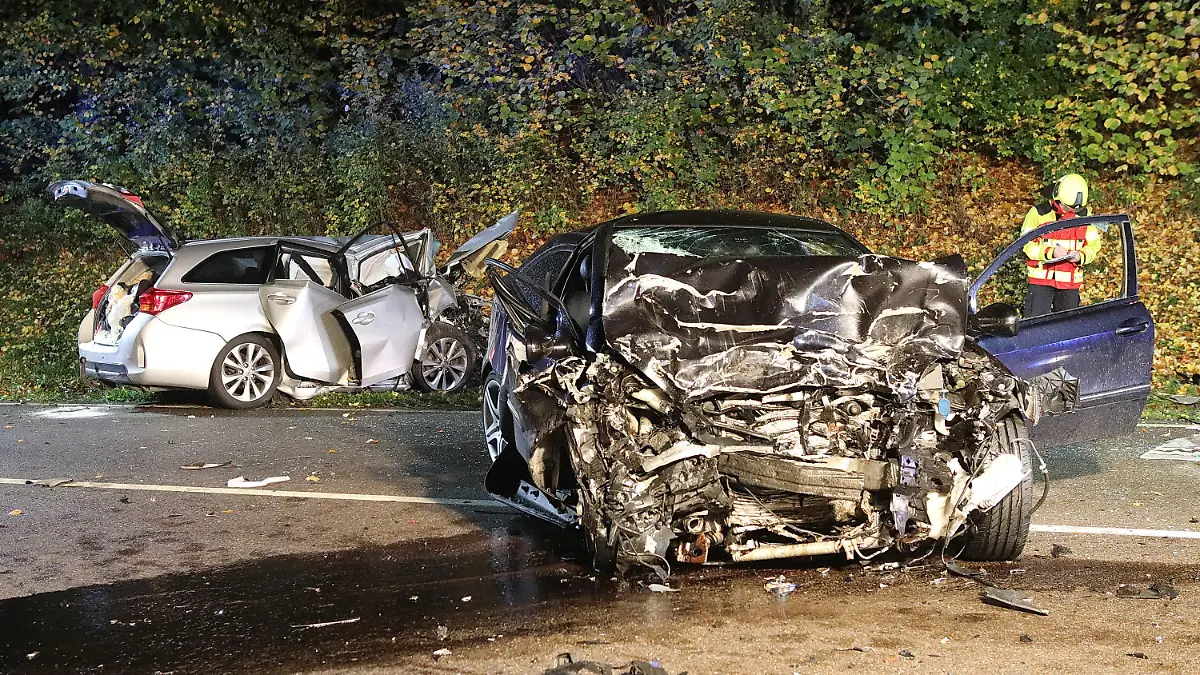 21.10.2022, Baden-Württemberg, Suppingen: Ein Feuerwehrmann steht zwischen den beiden stark zerstörten Wracks. Bei einem Frontalzusammenstoß der beiden Autos auf der B28 Höhe Suppingen (Alb-Donau-Kreis) sind die jeweiligen Fahrer gestorben. Ein 43-Jähriger und ein 62-Jähriger stießen am Freitagabend aus bislang ungeklärten Gründen bei starkem Regen mit ihren Fahrzeugen frontal zusammen. Foto: Ralf Zwiebler/dpa +++ dpa-Bildfunk +++