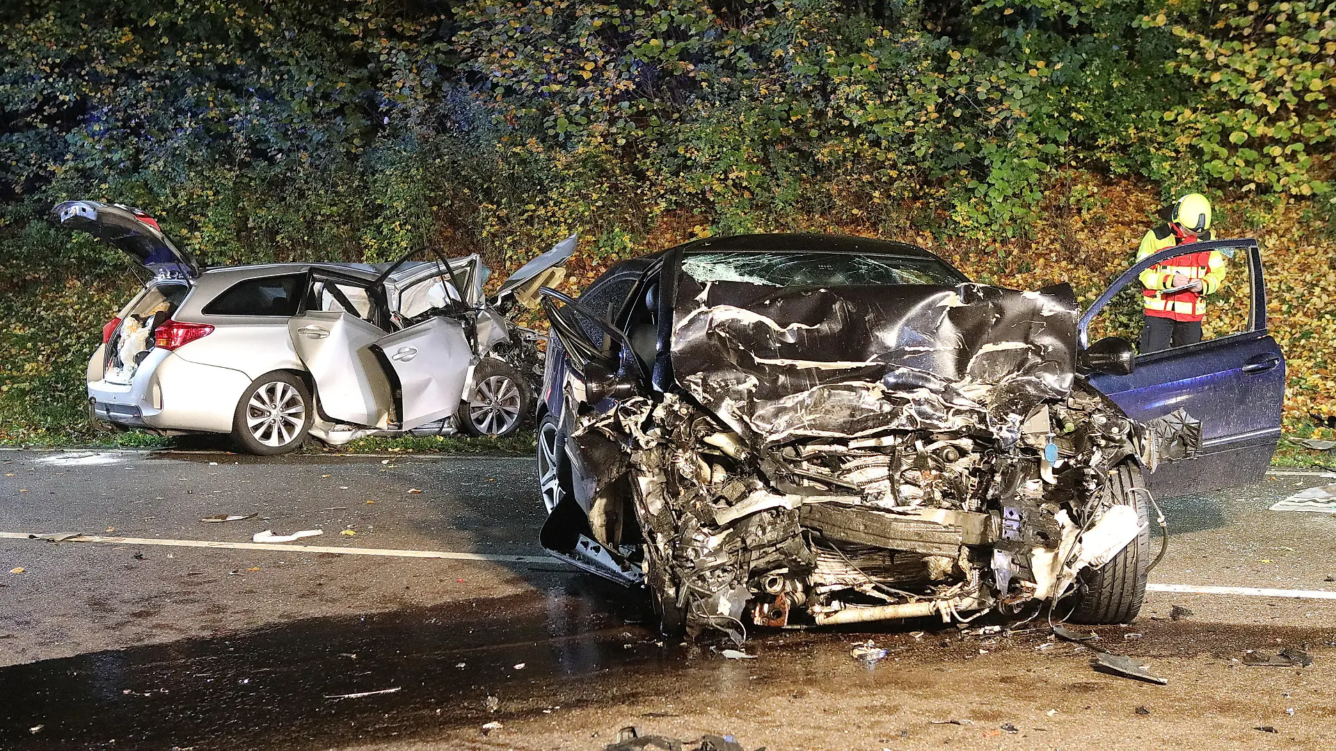 21.10.2022, Baden-Württemberg, Suppingen: Ein Feuerwehrmann steht zwischen den beiden stark zerstörten Wracks. Bei einem Frontalzusammenstoß der beiden Autos auf der B28 Höhe Suppingen (Alb-Donau-Kreis) sind die jeweiligen Fahrer gestorben. Ein 43-Jähriger und ein 62-Jähriger stießen am Freitagabend aus bislang ungeklärten Gründen bei starkem Regen mit ihren Fahrzeugen frontal zusammen. Foto: Ralf Zwiebler/dpa +++ dpa-Bildfunk +++