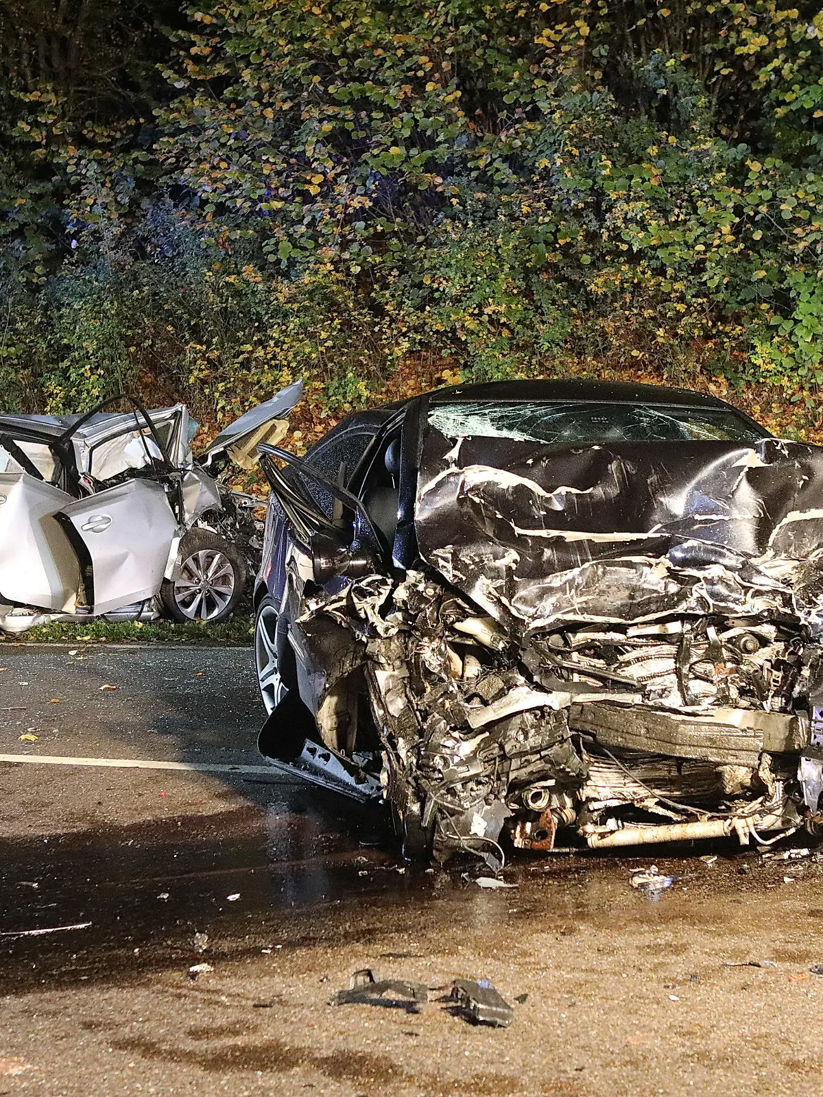21.10.2022, Baden-Württemberg, Suppingen: Ein Feuerwehrmann steht zwischen den beiden stark zerstörten Wracks. Bei einem Frontalzusammenstoß der beiden Autos auf der B28 Höhe Suppingen (Alb-Donau-Kreis) sind die jeweiligen Fahrer gestorben. Ein 43-Jähriger und ein 62-Jähriger stießen am Freitagabend aus bislang ungeklärten Gründen bei starkem Regen mit ihren Fahrzeugen frontal zusammen. Foto: Ralf Zwiebler/dpa +++ dpa-Bildfunk +++