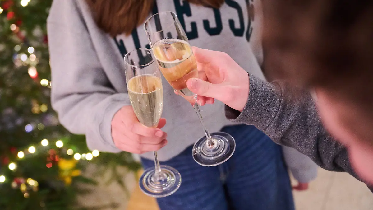 ARCHIV - 27.12.2022, Bayern, Freystadt: Zwei Personen stoßen zuhause neben einem Weihnachtsbaum mit Sekt an. (Illustration zu dpa: "Umfrage: Deutsche flüchten auch mit Alkohol vor dem Alltag") Foto: Annette Riedl/dpa +++ dpa-Bildfunk +++