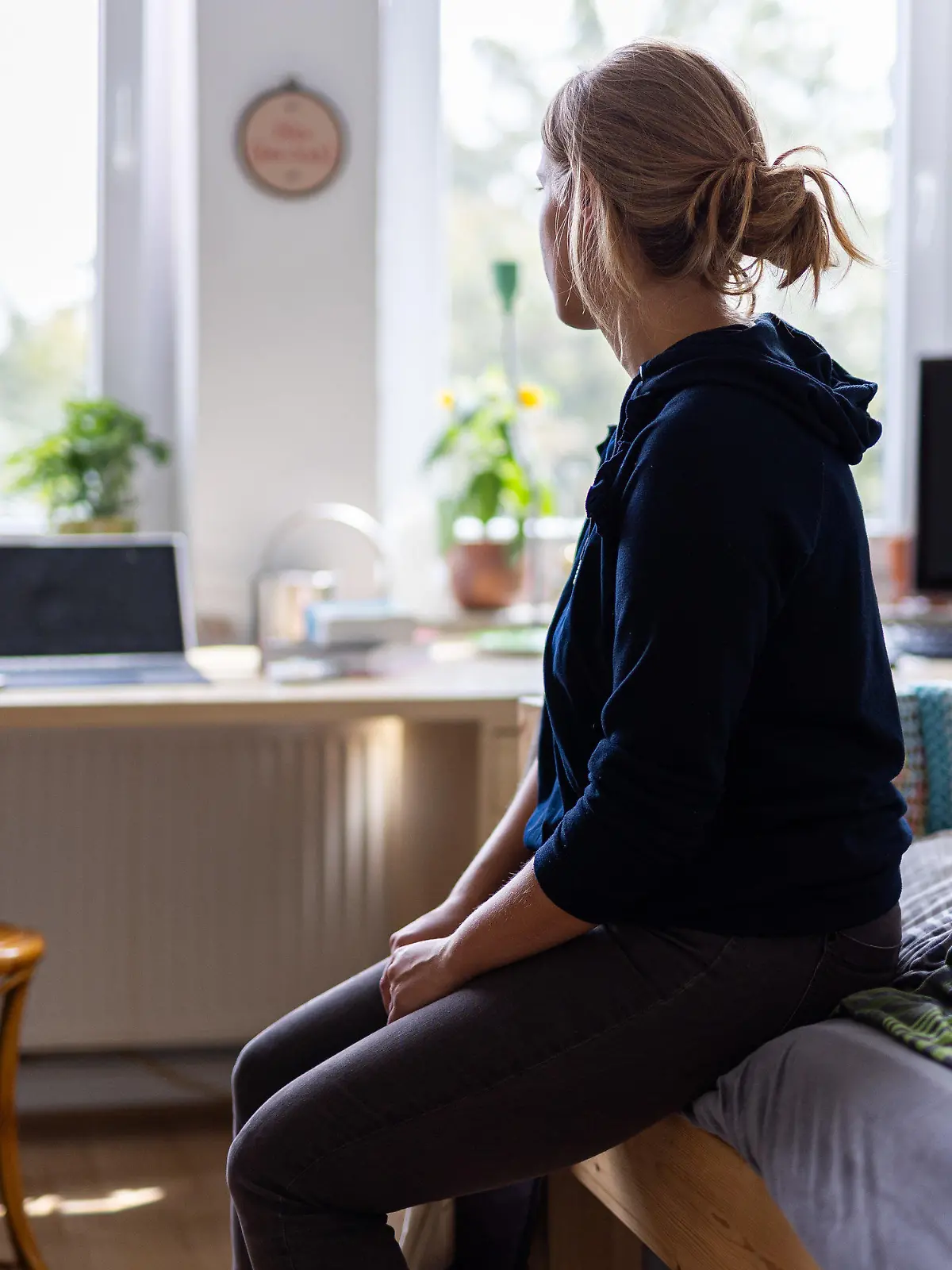 ARCHIV - 13.08.2023, Niedersachsen, Hannover: ILLUSTRATION - Eine Studentin sitzt auf dem Bett in ihrem WG-Zimmer und schaut aus dem Fenster (gestellte Szene). (Zu dpa "WHO will gegen Einsamkeit als Gesundheitsrisiko vorgehen") Foto: Michael Matthey/dpa - ACHTUNG: Nur zur redaktionellen Verwendung und nur mit vollständiger Nennung des vorstehenden Credits +++ dpa-Bildfunk +++