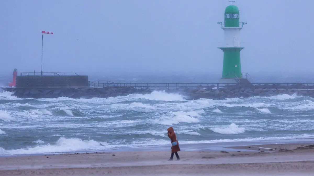 16.11.2023, Mecklenburg-Vorpommern, Rostock: Eine Frau geht bei Sturm und Regen über den Strand an der Ostseeküste in Warnemünde. In Mecklenburg-Vorpommern zeigt sich das Herbstwetter mit Böen, vielen Wolken und kräftigem Regen von seiner unfreundlichen Seite. Nach Angaben des Deutschen Wetterdienstes (DWD) kann es an der Küste zu Sturmböen mit bis zu 80 Kilometern pro Stunde kommen. Foto: Jens Büttner/dpa +++ dpa-Bildfunk +++