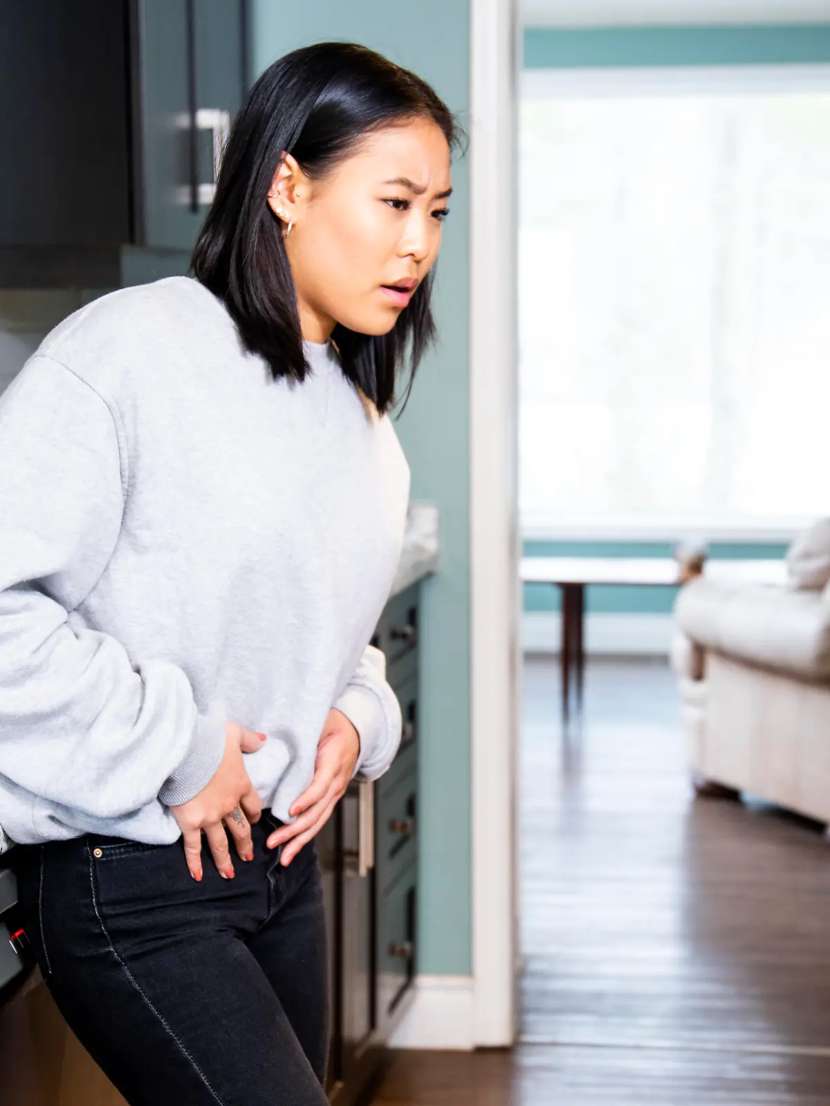 A young woman experiencing pelvic discomfort, she is grimacing in pain.