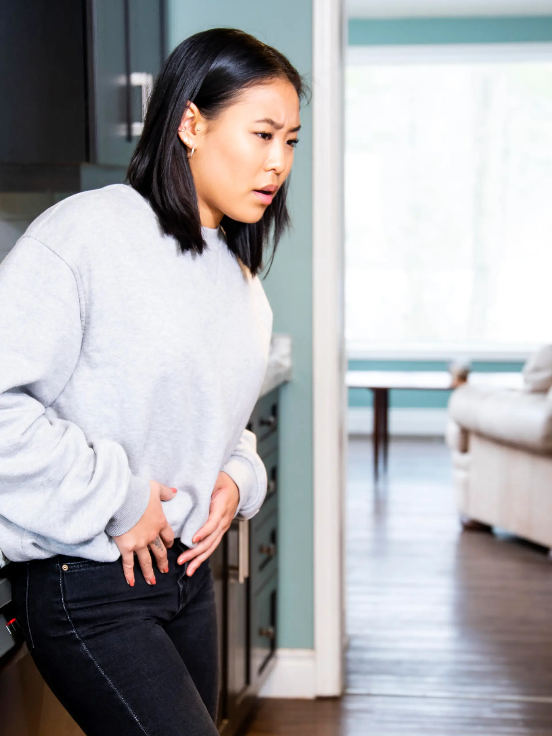 A young woman experiencing pelvic discomfort, she is grimacing in pain.