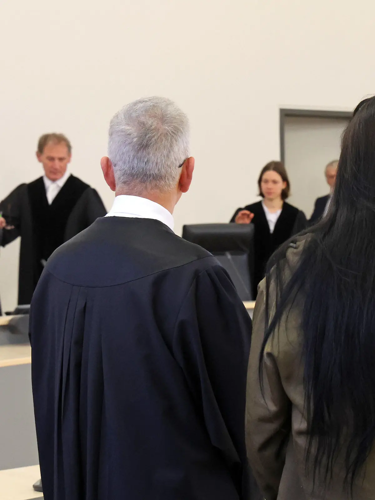19.12.2023, Mecklenburg-Vorpommern, Rostock: Ullrich Knye, Verteidiger, und die Angeklagte im Prozess wegen Mordes durch Unterlassung stehen im Saal des Landgerichts während des Einzugs des Gerichts und warten auf die Urteilsverkündung. Laut Anklage soll die 24-Jährige ihren einjährigen Sohn nicht ausreichend mit Nahrung und Flüssigkeit versorgt und keinen Arzt konsultiert haben, als er krank wurde. Stattdessen habe sie das Kind in ihrer Wohnung allein gelassen, um Zeit mit ihrem Freund zu verbringen. Der Junge starb im September 2021 infolge starken Durchfalls an einem Gerinnsel in den Lungenschlagadern. Foto: Bernd Wüstneck/dpa +++ dpa-Bildfunk +++