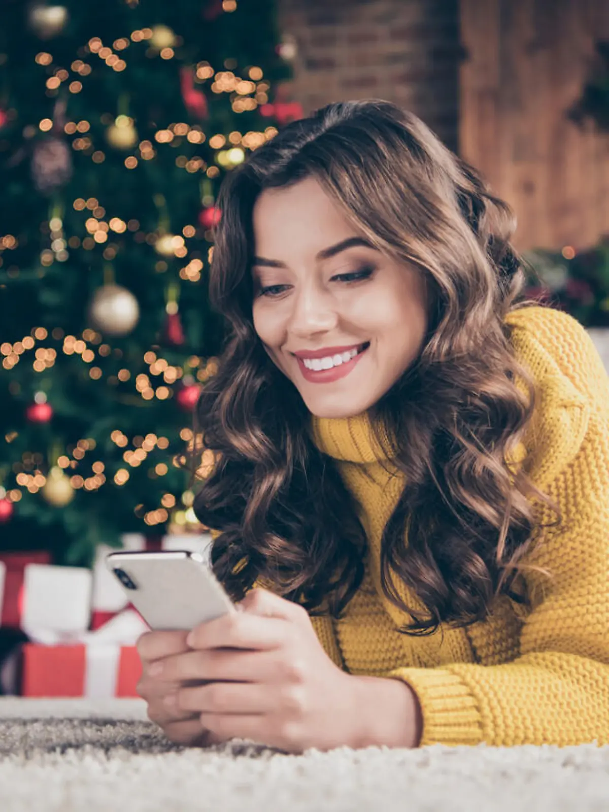 Low below angle view photo of charming, cute beautiful attractive girlfriend browsing through her phone in search of something while wearing jeans denim yellow sweater