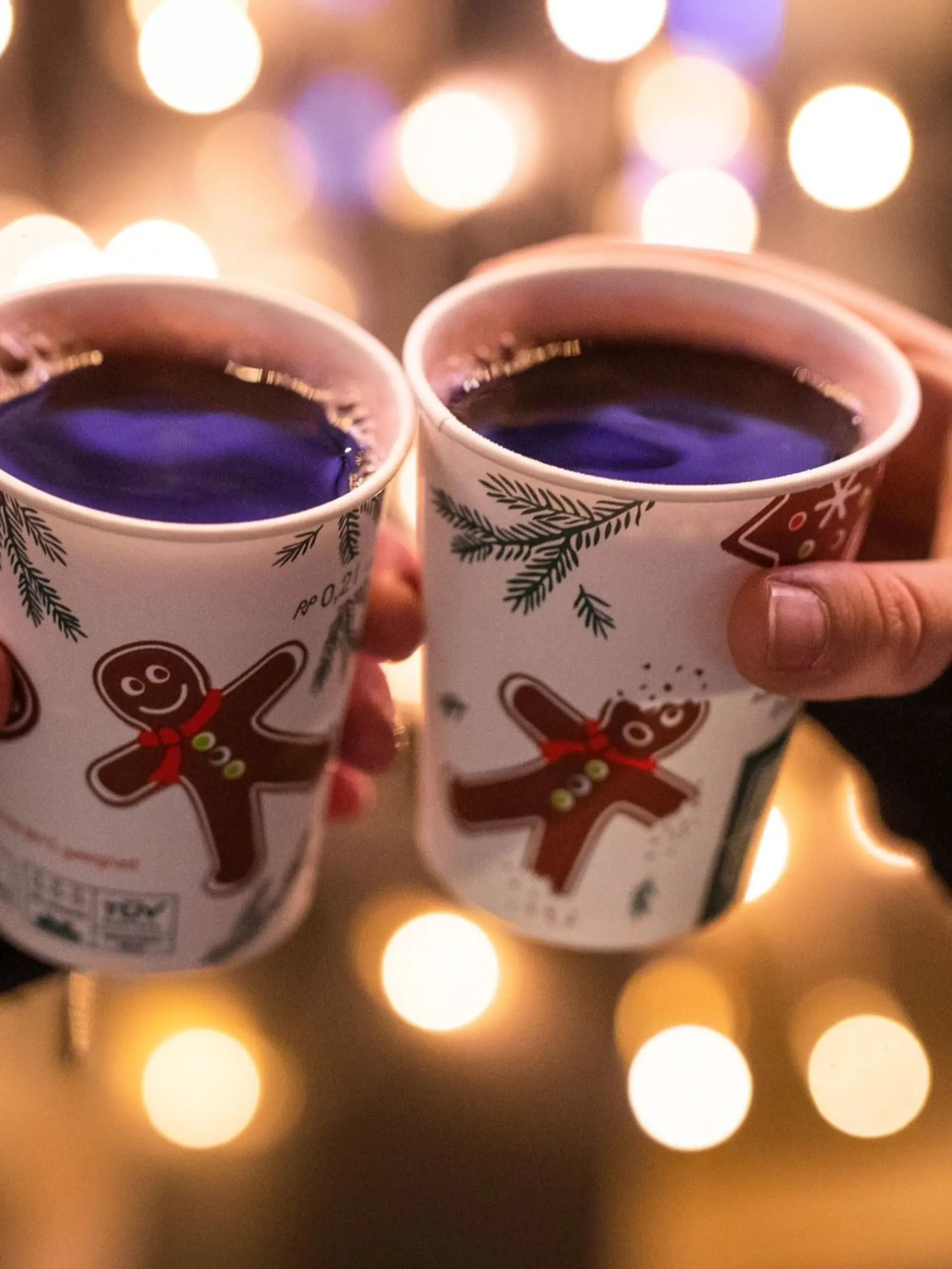 Zwei Besucherinnen eines Weihnachtsmarktes stoßen mit Glühwein an.