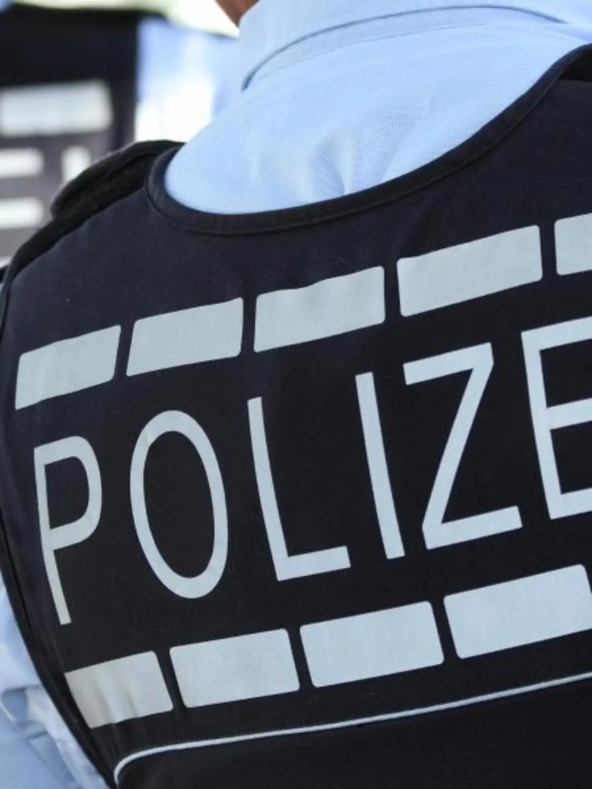 Ein Polizist trägt eine Weste mit der Aufschrift «Polizei»