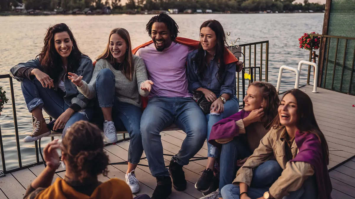 Group of Millennials having fun at the deck of houseboat. End of the summer weekend party.