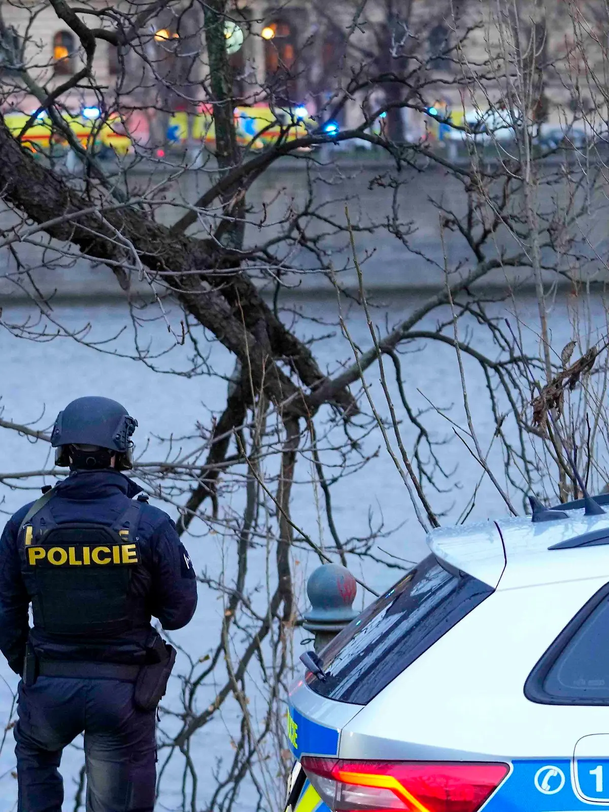 21.12.2023, Tschechien, Prag: Ein Polizist steht am Ufer der Moldau im Zentrum. An einer Hochschule in der Prager Innenstadt sollen Schüsse gefallen sein. Foto: Petr David Josek/AP/dpa +++ dpa-Bildfunk +++