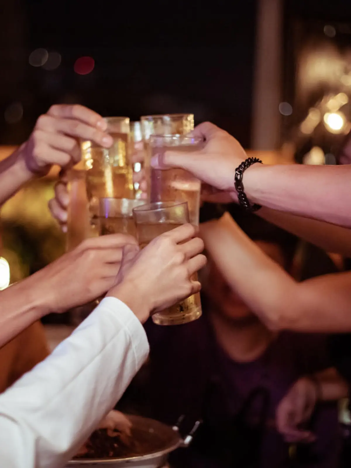 Group of young people hands toasting and cheering aperitif beers