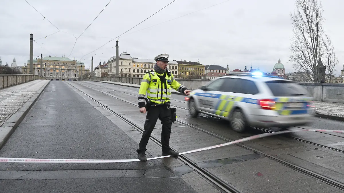 21.12.2023, Tschechien, Prag: Ein Polizist steht neben einem Polizeiauto auf der gesperrten Manes-Brücke. An einer Hochschule in der Prager Innenstadt sollen Schüsse gefallen sein. Foto: imánek Vít/CTK/dpa +++ dpa-Bildfunk +++