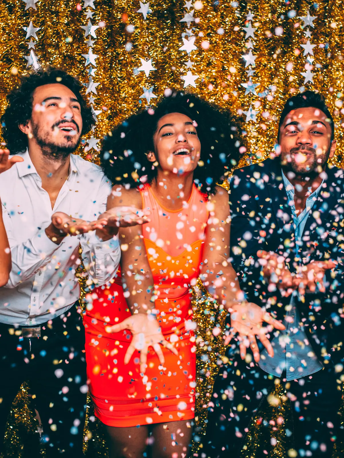 Friends blowing confetti at a new year's party.