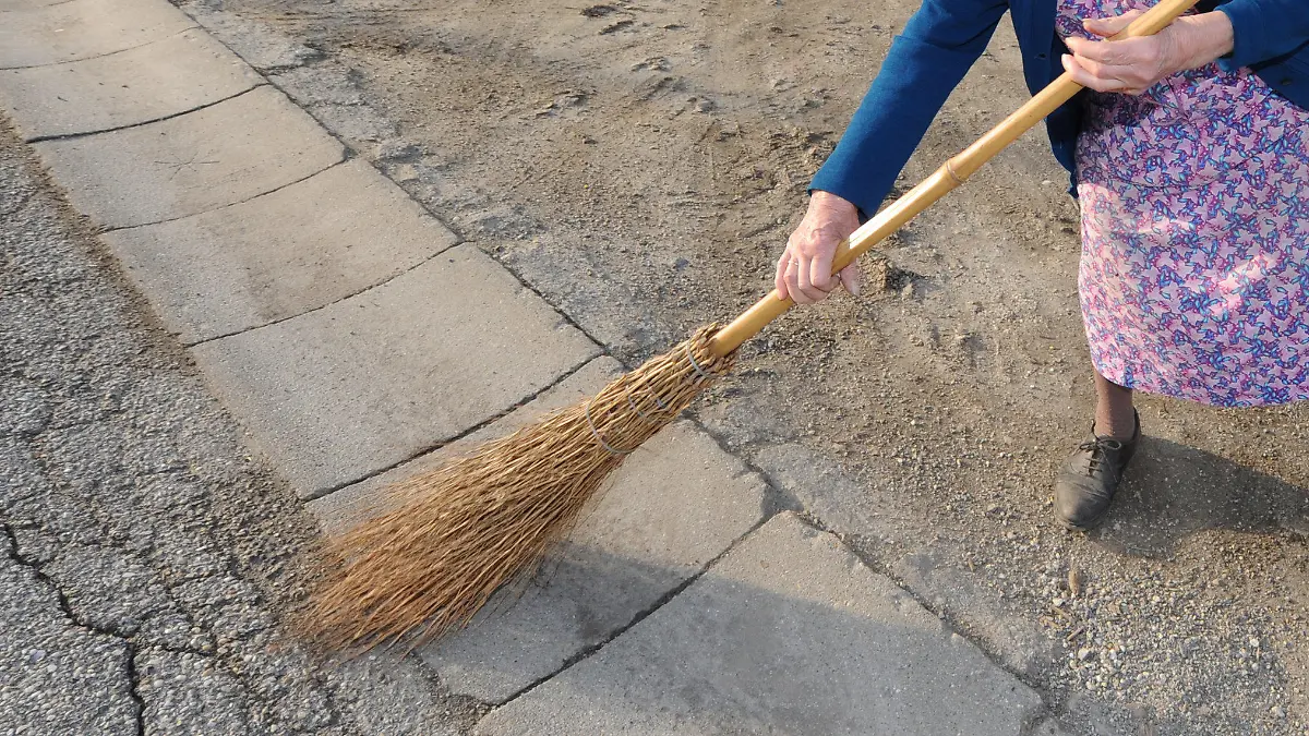 Anna Reitinger kehrt am Mittwoch (17.03.2010) in Allkofen (Niederbayern) mit einem Besen die Straße. In den nächsten Tagen soll es nach Angaben der Meteorologen mild und frühlingshaft werden. Foto: Armin Weigel dpa/lby +++(c) dpa - Bildfunk+++