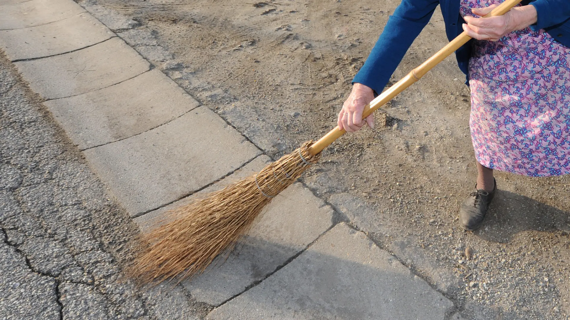 Anna Reitinger kehrt am Mittwoch (17.03.2010) in Allkofen (Niederbayern) mit einem Besen die Straße. In den nächsten Tagen soll es nach Angaben der Meteorologen mild und frühlingshaft werden. Foto: Armin Weigel dpa/lby  +++(c) dpa - Bildfunk+++