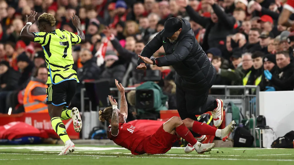 Liverpool, England, 23rd December 2023. Kostas Tsimikas of Liverpool challenges Bukayo Saka of Arsenal and goes crashing into Jurgen Klopp manager of Liverpool leading to Tsimikas injury during the Premier League match at Anfield, Liverpool. Picture credit should read: Darren Staples / Sportimage EDITORIAL USE ONLY. No use with unauthorised audio, video, data, fixture lists, club/league logos or live services. Online in-match use limited to 120 images, no video emulation. No use in betting, games or single club/league/player publications. SPI-2829-0038