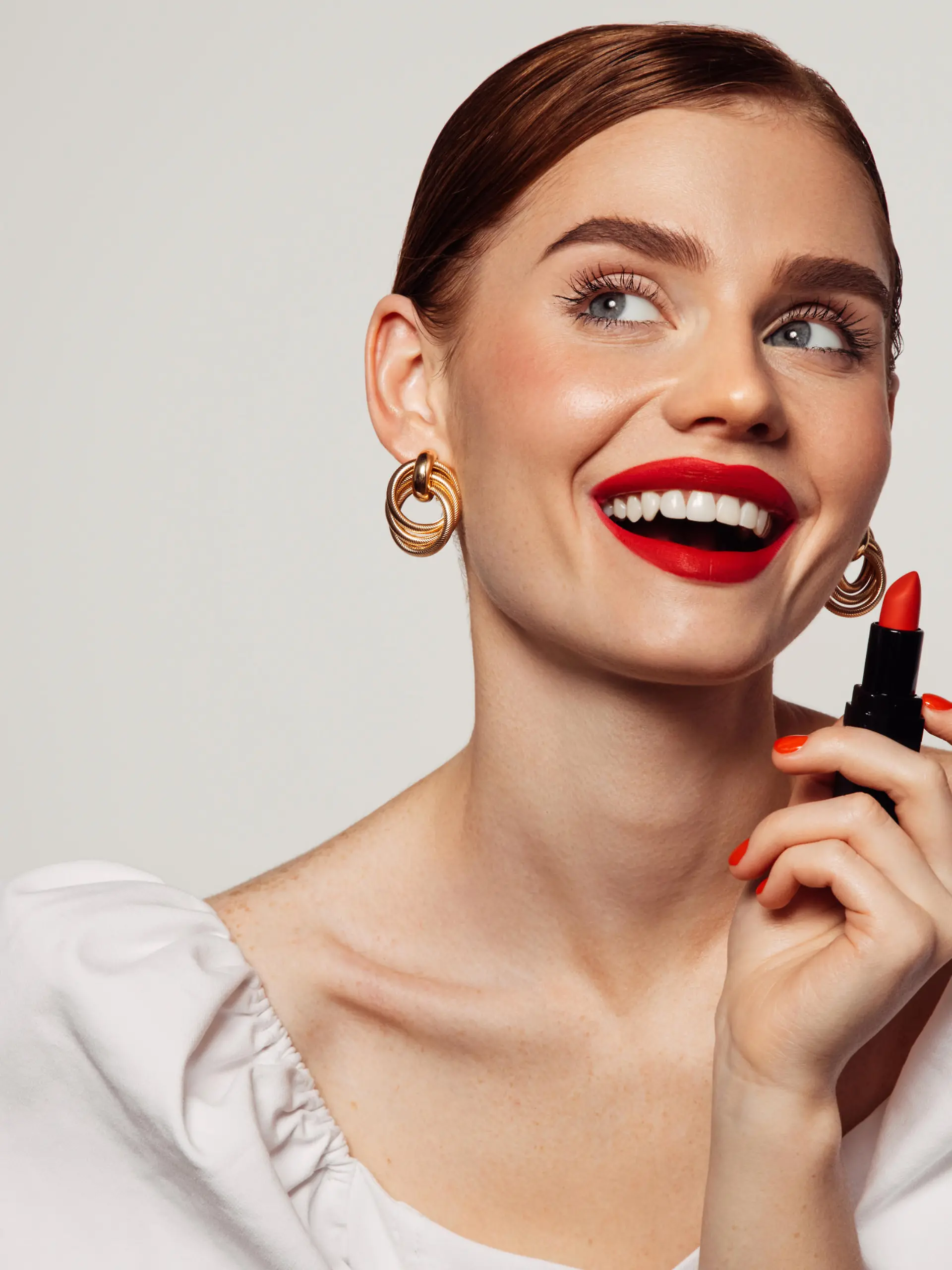 Beautiful emotional woman with bright make-up applying red lipstick