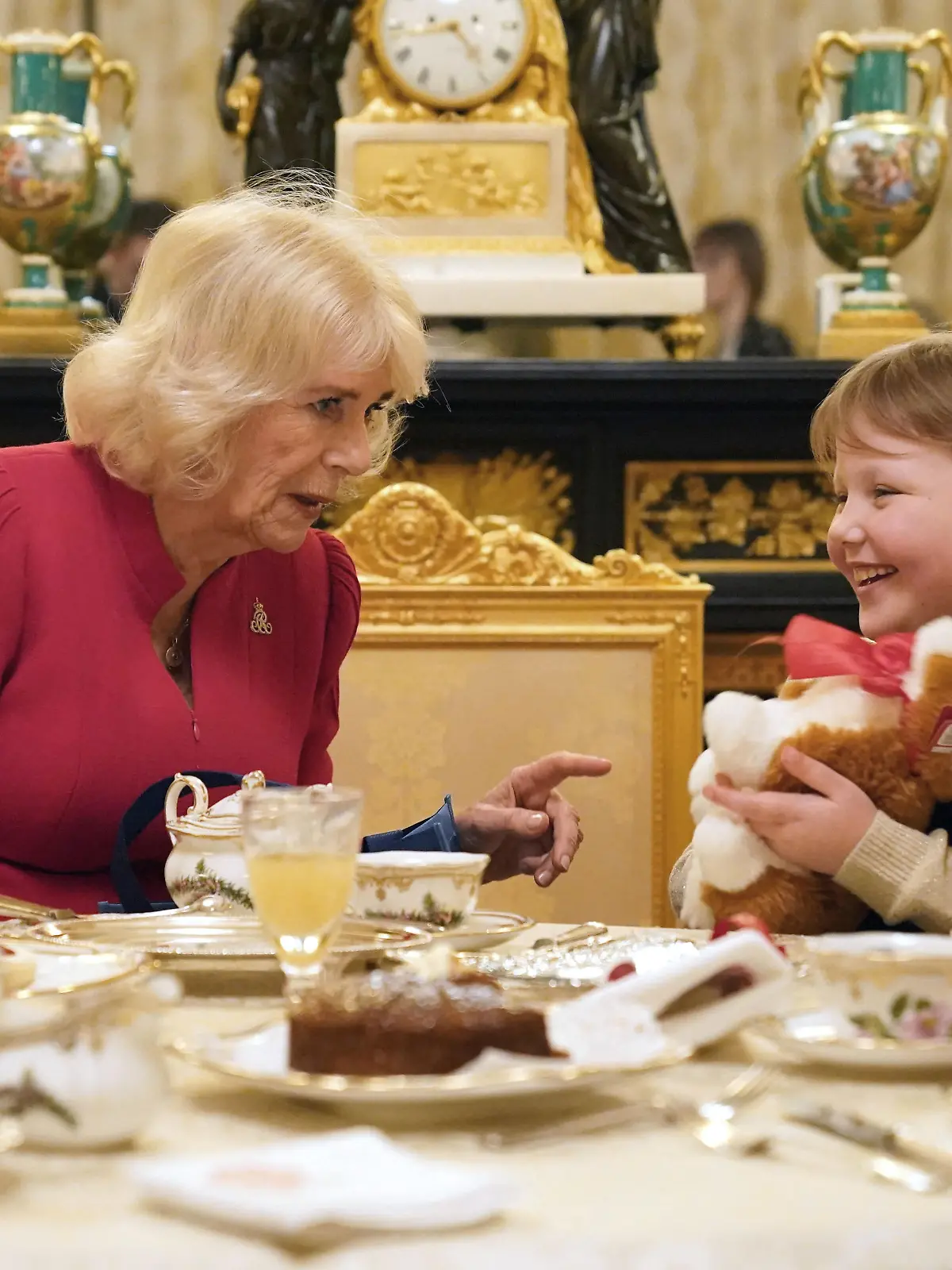 Queen Camilla presents seven-year-old Olivia Taylor from Sidcup with a corgi Christmas present whilst taking tea at Windsor Castle, Berkshire. The blind schoolgirl with a brain tumour sang a Christmas song and gave the Queen a handmade ring when she was invited to Windsor Castle., Credit:Jonathan Brady / Avalon / 261223