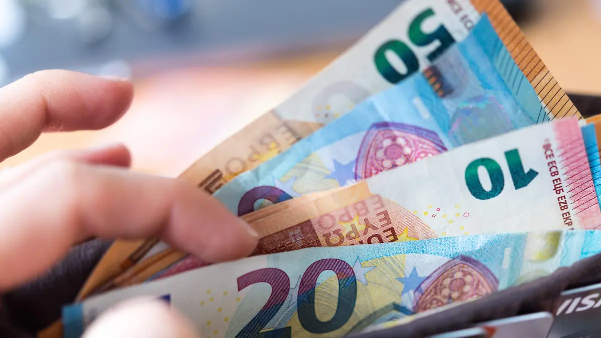 ARCHIV - 04.12.2018, Sachsen, Dresden: ILLUSTRATION - Eine Frau hält ein Portemonnaie in der Hand, in dem Geldscheine stecken. Der Bundestag soll am Donnerstag über das neue Bürgergeld abstimmen. Foto: Monika Skolimowska/dpa-Zentralbild/dpa +++ dpa-Bildfunk +++