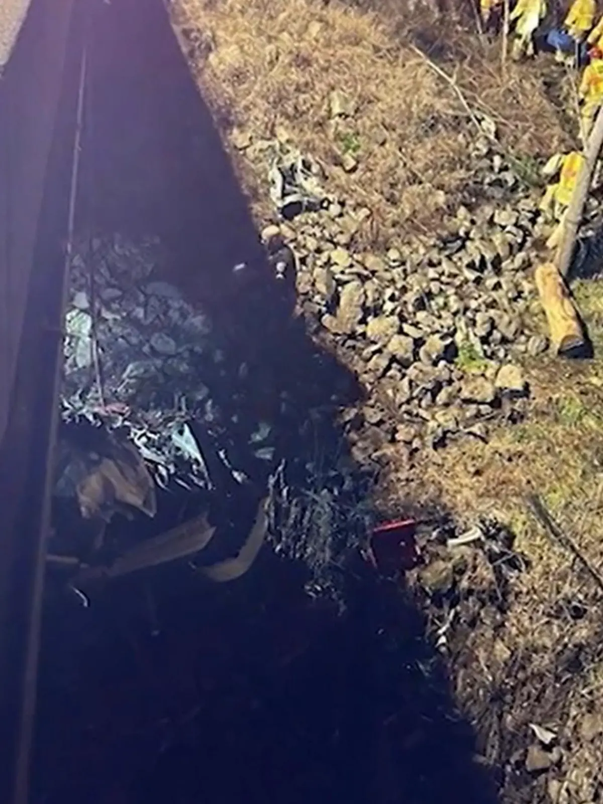 Ein Autowrack in einem Flussbett unterhalb einer Autobahnbrücke.