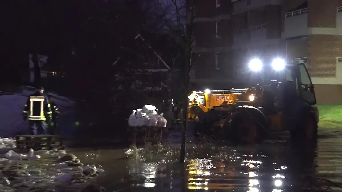 Rettungskräfte fahren mit einem Radlader Sandsäcke hin und her, um den Wümme-Deich zu sichern.