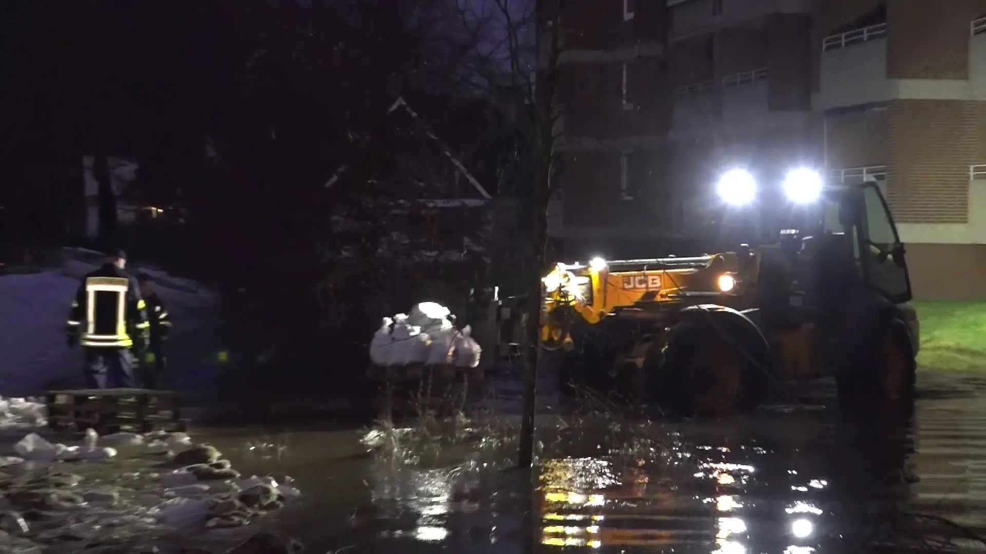 Rettungskräfte fahren mit einem Radlader Sandsäcke hin und her, um den Wümme-Deich zu sichern.