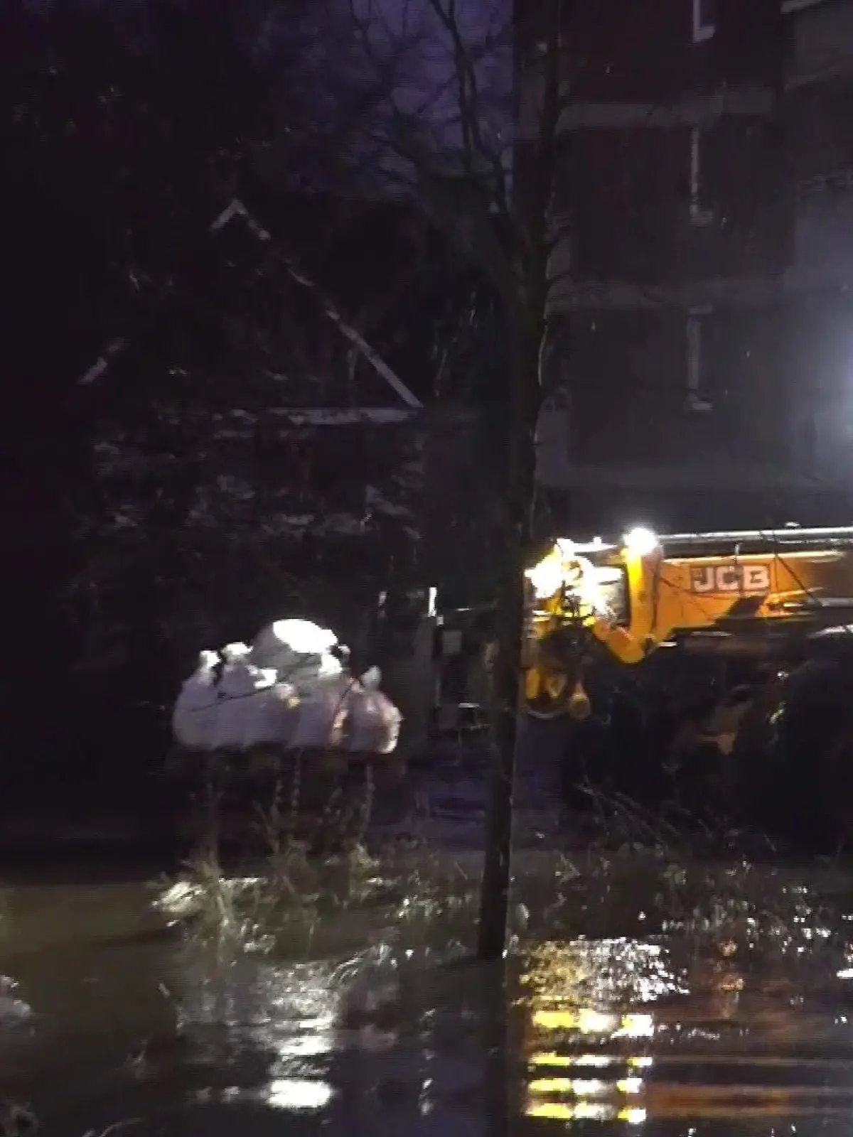 Rettungskräfte fahren mit einem Radlader Sandsäcke hin und her, um den Wümme-Deich zu sichern.
