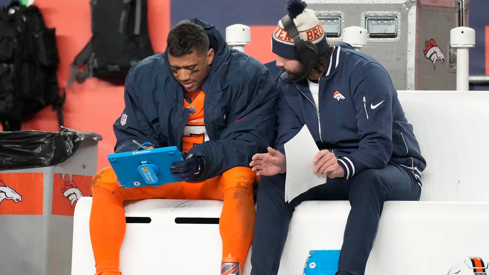 Denver Broncos quarterback Russell Wilson, left, looks over plays during the second half of an NFL football game against the New England Patriots, Sunday, Dec. 24, 2023, in Denver. (AP Photo/David Zalubowski)
