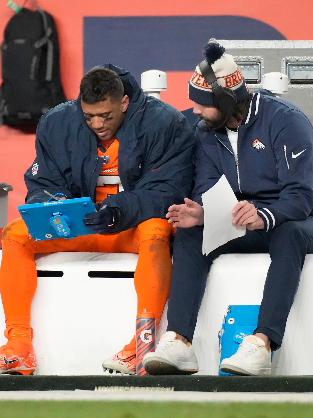 Denver Broncos quarterback Russell Wilson, left, looks over plays during the second half of an NFL football game against the New England Patriots, Sunday, Dec. 24, 2023, in Denver. (AP Photo/David Zalubowski)