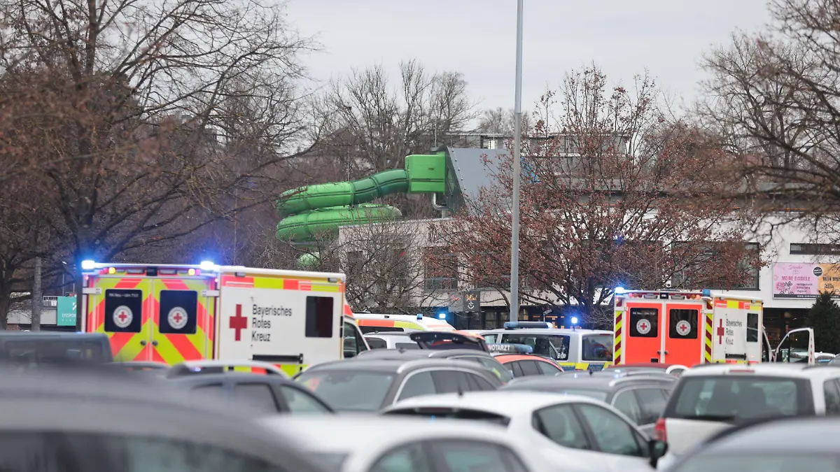 28.12.2023, Bayern, Neu-Ulm: Zahlreiche Einsatzkräfte stehen auf dem vollen Parkplatz eines Erlebnisbades in Neu-Ulm. Ein Junge im Grundschulalter wurde hier bei einem Unfall schwer bis lebensgefährlich verletzt. Foto: Ralf Zwiebler/dpa +++ dpa-Bildfunk +++