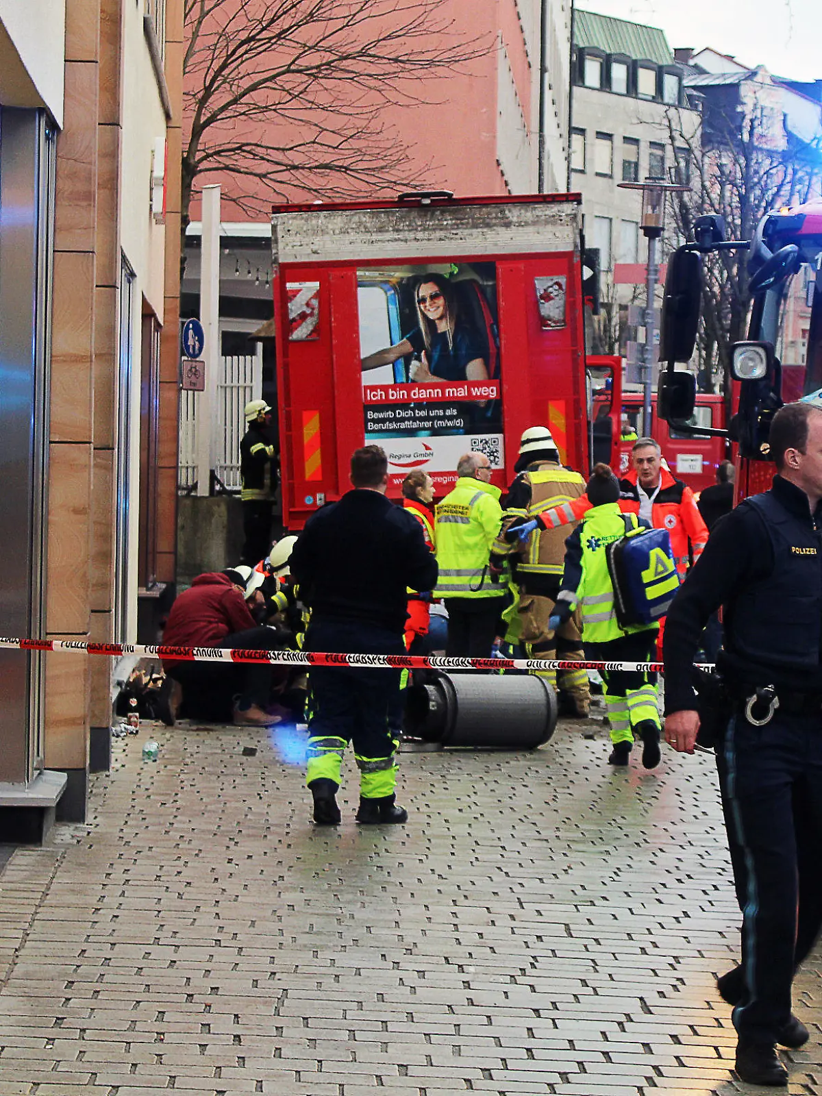 29.12.2023, Bayern, Passau: Einsatzkräfte von Feuerwehr und Rettungsdienst stehen in der Innenstadt am Einsatzort. Ein Lastwagen ist in der Passauer Innenstadt in eine Fußgängergruppe gefahren und hat dabei mehrere Menschen verletzt und eine Frau getötet. Auch der Lastwagenfahrer sei auf dem Weg ins Krankenhaus, sagte ein Polizeisprecher. Foto: -/Zema Medien/dpa +++ dpa-Bildfunk +++