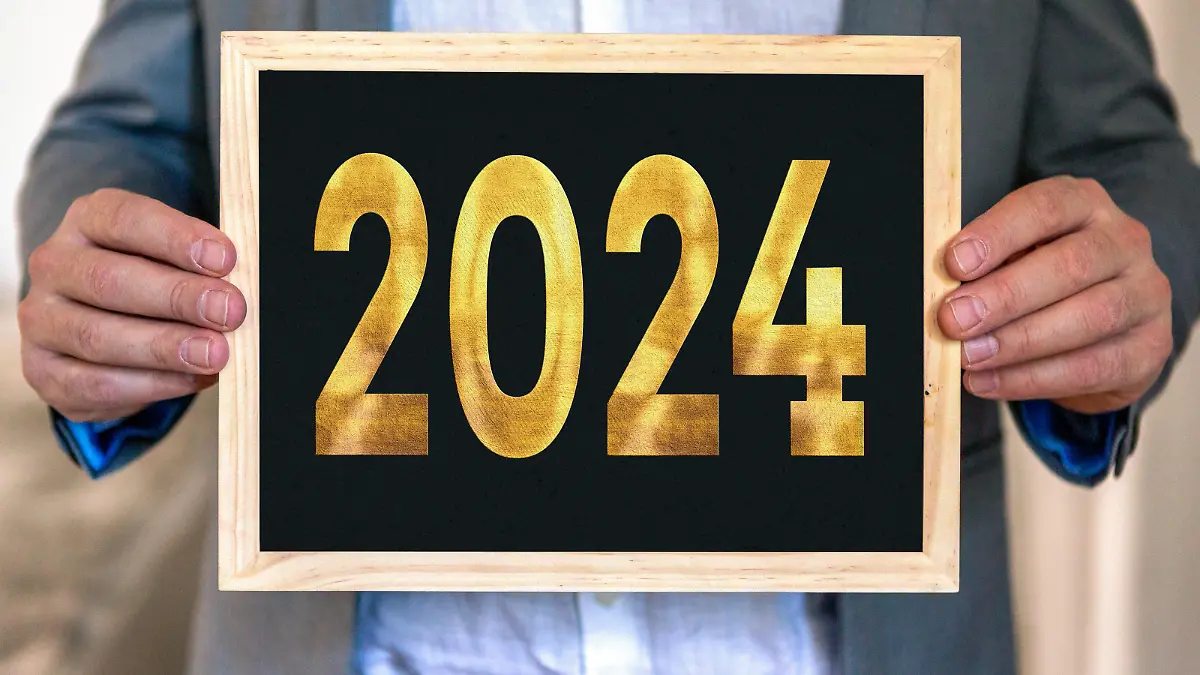December 28, 2023: Man in suit holding a plaque with the number 2024 in gold lettering. New Year and New Year's Eve concept PHOTOMONTAGE *** Mann in Anzug hält eine Tafel mit der Zahl 2024 in goldener Schrift. Neujahr und Silvester Konzept FOTOMONTAGE