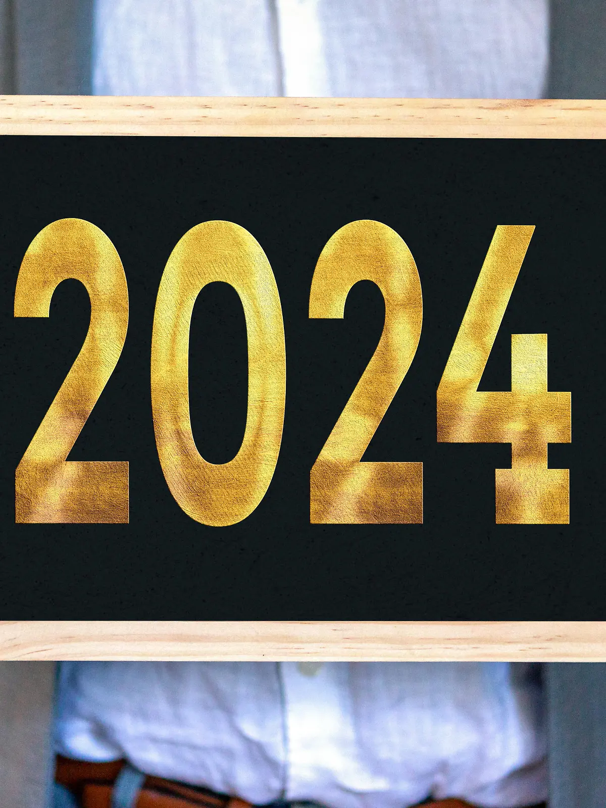 December 28, 2023: Man in suit holding a plaque with the number 2024 in gold lettering. New Year and New Year's Eve concept PHOTOMONTAGE *** Mann in Anzug hält eine Tafel mit der Zahl 2024 in goldener Schrift. Neujahr und Silvester Konzept FOTOMONTAGE