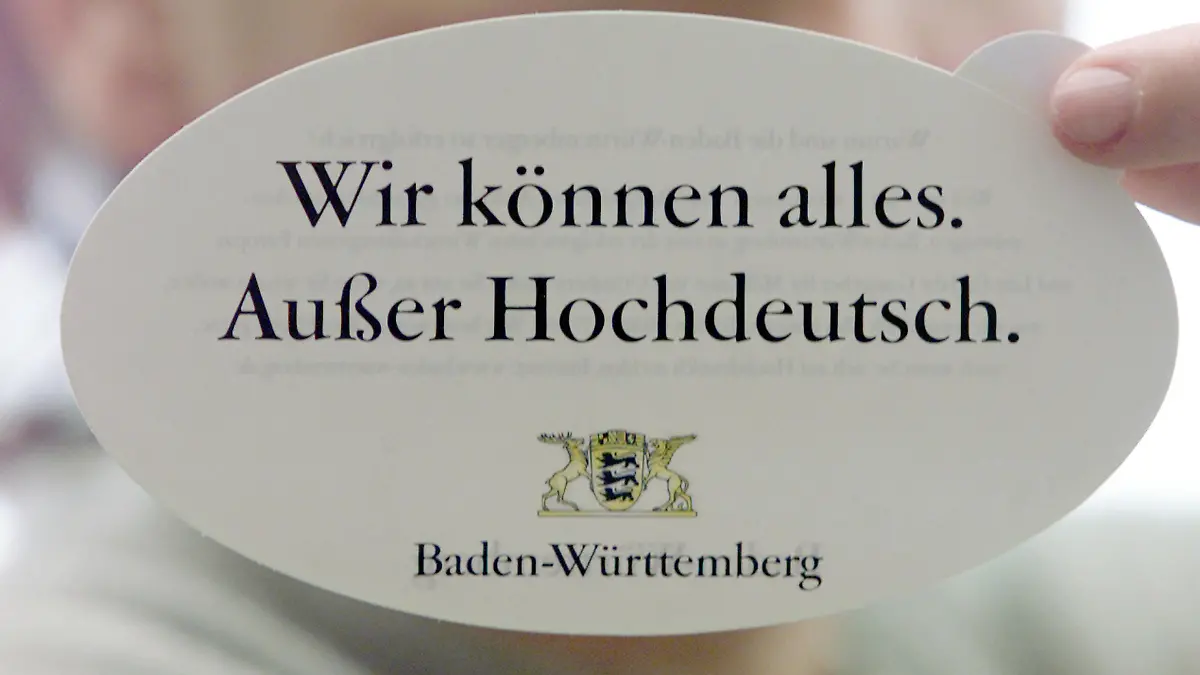 ** ARCHIV ** Einen Aufkleber mit dem offiziellen Slogan der Imagekampagne des Landes Baden-Wuerttemberg "Wir koennen alles. Ausser Hochdeutsch." haelt diese junge Dame am 26. Januar 2000, in Stuttgart. Laender und Regionen werben mit Imagekampagnen um Investoren und Fachkraefte. (AP Photo/Thomas Kienzle) ** ZU KORR **