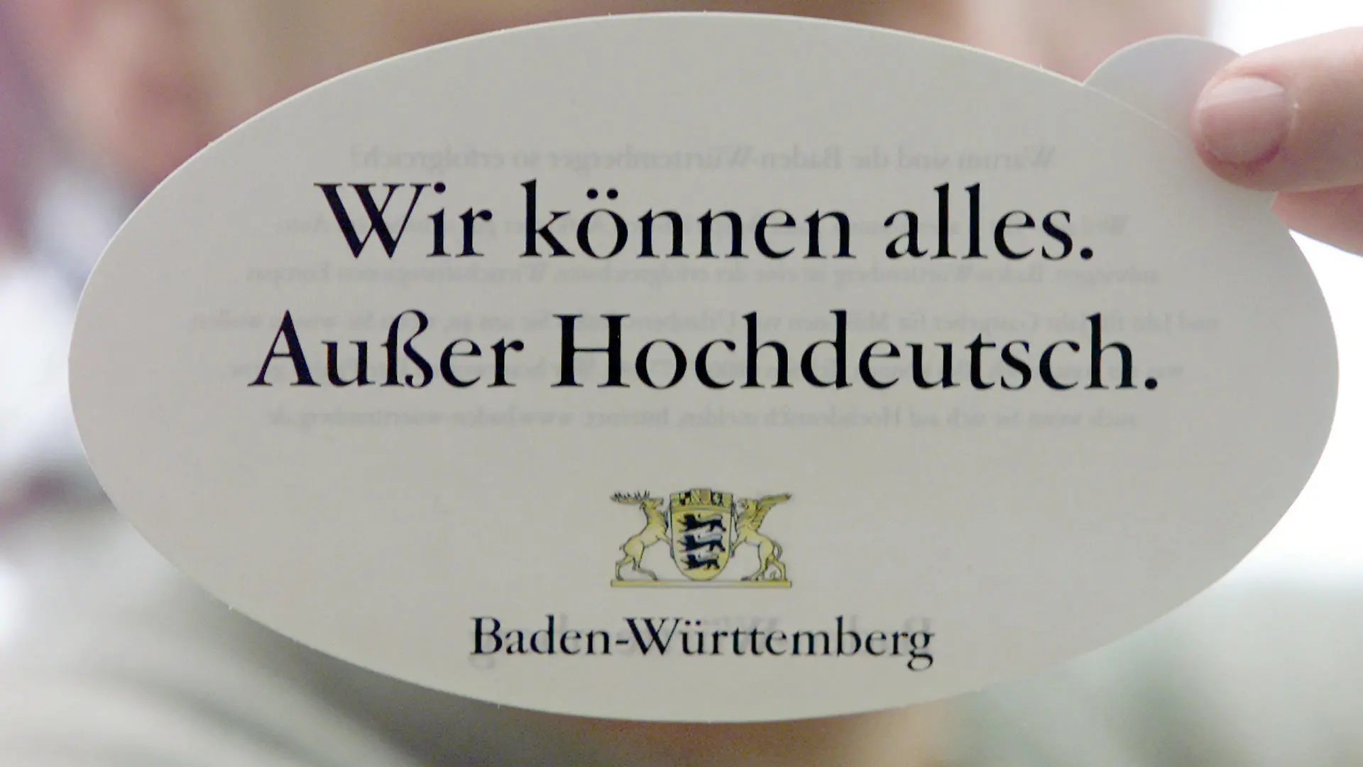 ** ARCHIV ** Einen Aufkleber mit dem offiziellen Slogan der Imagekampagne des Landes Baden-Wuerttemberg "Wir koennen alles. Ausser Hochdeutsch." haelt diese junge Dame am 26. Januar 2000, in Stuttgart. Laender und Regionen werben mit Imagekampagnen um Investoren und Fachkraefte. (AP Photo/Thomas Kienzle) ** ZU KORR **