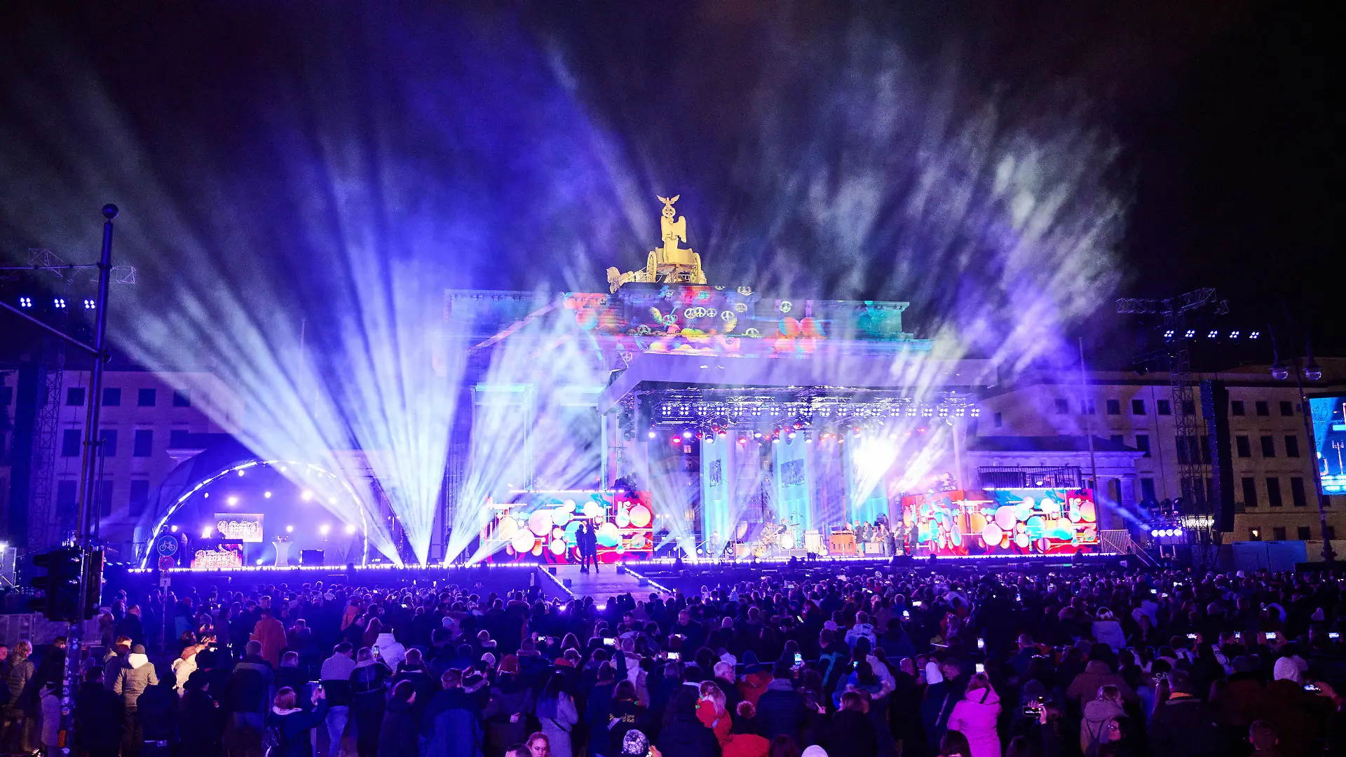 31.12.2023, Berlin: Einige Tausend Menschen befinden sich schon bei der Party ·Celebrate at the Gate· am Brandenburger Tor und hören Musik verschiedener Künstler, moderiert von Nick Sawatzki des Radiosenders 94,3 RS2. Nach mehreren Jahren Pause gibt es wieder ein Höhenfeuerwerk zu Silvester. Laut Veranstalter könnten 65 000 Menschen kommen. Foto: Annette Riedl/dpa +++ dpa-Bildfunk +++