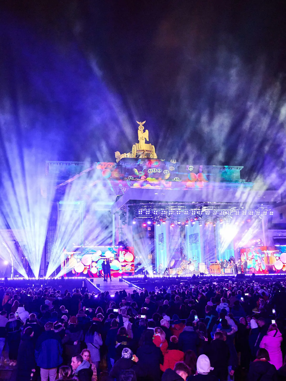 31.12.2023, Berlin: Einige Tausend Menschen befinden sich schon bei der Party ·Celebrate at the Gate· am Brandenburger Tor und hören Musik verschiedener Künstler, moderiert von Nick Sawatzki des Radiosenders 94,3 RS2. Nach mehreren Jahren Pause gibt es wieder ein Höhenfeuerwerk zu Silvester. Laut Veranstalter könnten 65 000 Menschen kommen. Foto: Annette Riedl/dpa +++ dpa-Bildfunk +++