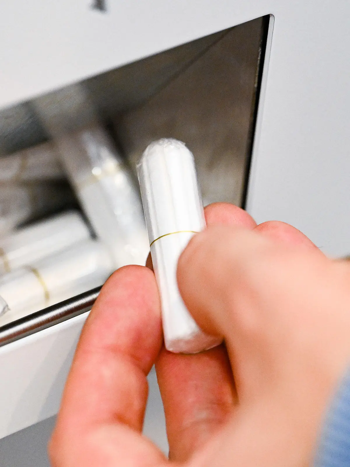 20.10.2022, Baden-Württemberg, Stuttgart: Eine Hand nimmt auf einer Herrentoilette im Rathaus einen Tampon aus einem Tampon-Spender. Die Initiative geht auf die Grünen-Fraktion im Gemeinderat zurück - Ziel ist die Gleichberechtigung von Transmenschen.       (zu dpa: "Tampon-Spender auf Herrenklo im Stuttgarter Rathaus - OB ärgert sich") Foto: Bernd Weißbrod/dpa +++ dpa-Bildfunk +++