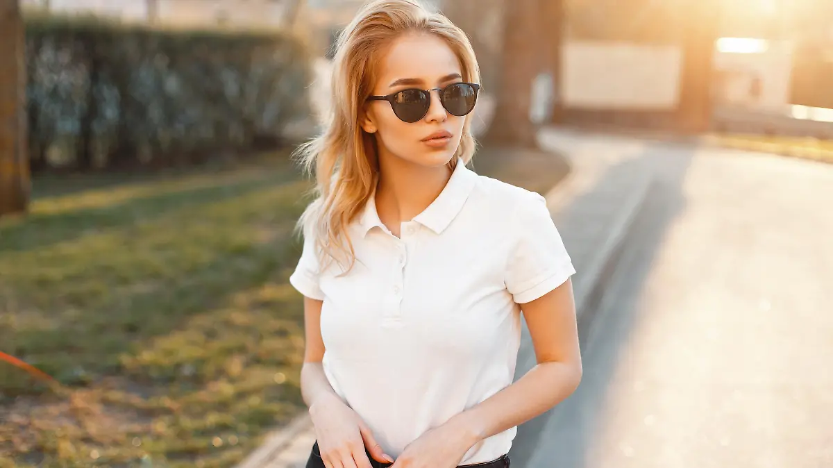 Young girl in trendy sunglasses and white polo shirt in a spring day at sunset