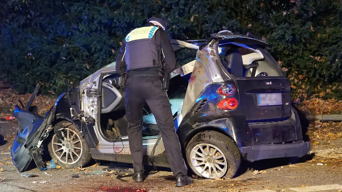 18.10.2022, Hamburg: Ein Polizist steht neben einem Unfallwagen. Bei einem Unfall im Hamburger Stadtteil Farmsen-Berne ist ein Autofahrer lebensgefährlich verletzt worden. Der Mann fuhr vermutlich mit überhöhter Geschwindigkeit und verlor die Kontrolle über sein Auto, wie eine Polizeisprecherin am frühen Mittwochmorgen sagte. Daraufhin überschlug sich das Auto mehrfach, kollidierte mit einem in gleicher Richtung fahrenden Pkw und blieb schließlich auf der Seite liegen. Der Fahrer musste laut Sprecherin von der Feuerwehr befreit werden; er kam mit lebensgefährlichen Verletzungen in ein Krankenhaus. Der zweite Fahrer wurde bei dem Unfall leicht verletzt. Foto: citynewstv/dpa +++ dpa-Bildfunk +++