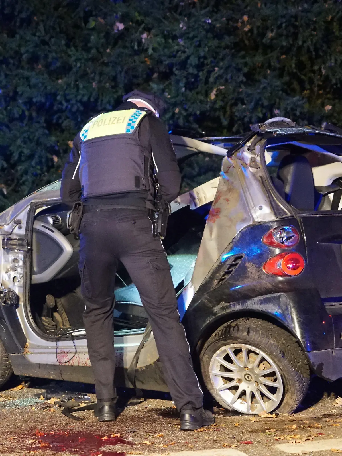 18.10.2022, Hamburg: Ein Polizist steht neben einem Unfallwagen. Bei einem Unfall im Hamburger Stadtteil Farmsen-Berne ist ein Autofahrer lebensgefährlich verletzt worden. Der Mann fuhr vermutlich mit überhöhter Geschwindigkeit und verlor die Kontrolle über sein Auto, wie eine Polizeisprecherin am frühen Mittwochmorgen sagte. Daraufhin überschlug sich das Auto mehrfach, kollidierte mit einem in gleicher Richtung fahrenden Pkw und blieb schließlich auf der Seite liegen. Der Fahrer musste laut Sprecherin von der Feuerwehr befreit werden; er kam mit lebensgefährlichen Verletzungen in ein Krankenhaus. Der zweite Fahrer wurde bei dem Unfall leicht verletzt. Foto: citynewstv/dpa +++ dpa-Bildfunk +++