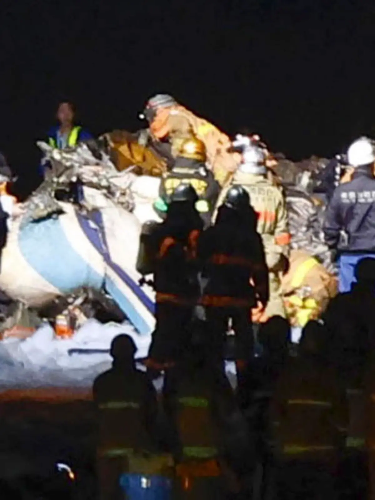 CORRECTS TO THE PART OF THE JAPANESE COAST GUARD AIRCRAFT - Firefighters inspect a part of the Japanese coast guard aircraft on the runway of Haneda airport on Tuesday, Jan. 2, 2024, in Tokyo, Japan. A passenger plane collided with the Japanese coast guard aircraft and burst into flames at the airport on Tuesday, officials said. (Kyodo News via AP)