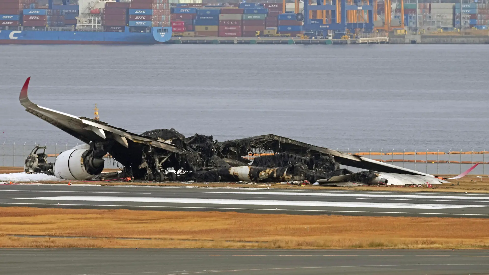 03.01.2024, Japan, Tokio: Das ausgebrannte Flugzeug der Japan Airlines ist auf dem Flughafen Haneda zu sehen. Ein Passagierflugzeug der Japan Airlines (JAL) stieß am Dienstag aus noch ungeklärter Ursache unmittelbar nach der Landung mit einem Flugzeug der japanischen Küstenwache zusammen, das Hilfsgüter zu Überlebenden der Erdbebenkatastrophe auf der Halbinsel Noto bringen sollte. Fünf Menschen an Bord des Küstenwachenflugzeugs kamen dabei ums Leben. Foto: Uncredited/Kyodo News/AP +++ dpa-Bildfunk +++