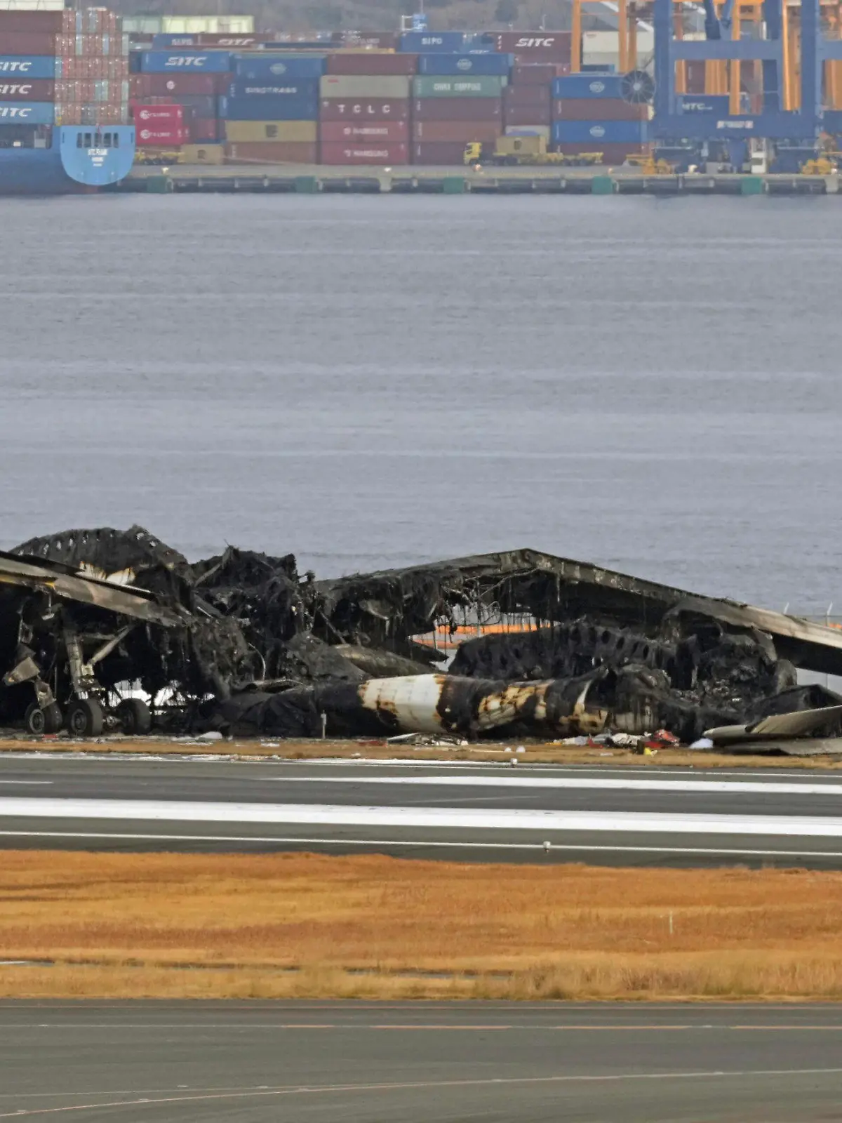 03.01.2024, Japan, Tokio: Das ausgebrannte Flugzeug der Japan Airlines ist auf dem Flughafen Haneda zu sehen. Ein Passagierflugzeug der Japan Airlines (JAL) stieß am Dienstag aus noch ungeklärter Ursache unmittelbar nach der Landung mit einem Flugzeug der japanischen Küstenwache zusammen, das Hilfsgüter zu Überlebenden der Erdbebenkatastrophe auf der Halbinsel Noto bringen sollte. Fünf Menschen an Bord des Küstenwachenflugzeugs kamen dabei ums Leben. Foto: Uncredited/Kyodo News/AP +++ dpa-Bildfunk +++
