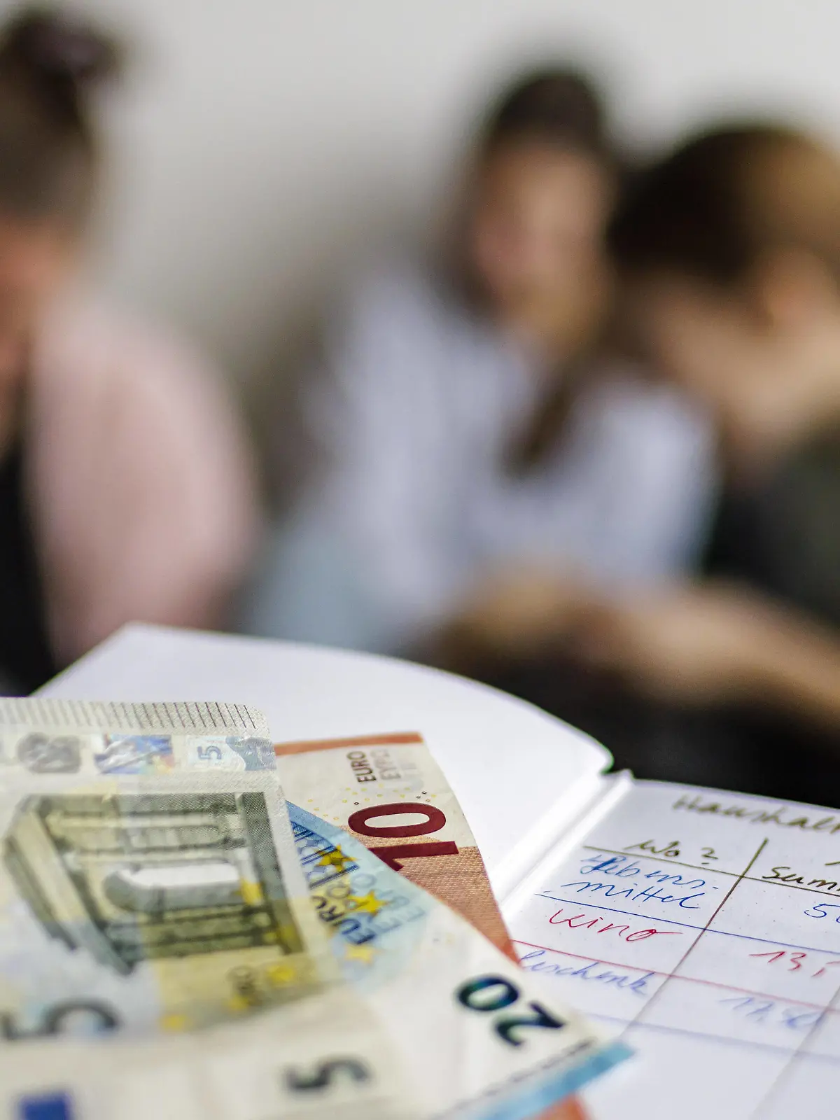 Haushaltsbuch mit fuenfunddreissig Euro. Im Hintergrund eine Mutter mit drei Kindern. Bonn Deutschland *** Household book with fuenfunddreissig euro In the background a mother with three children Bonn Germany Copyright: xUtexGrabowsky/photothek.dex