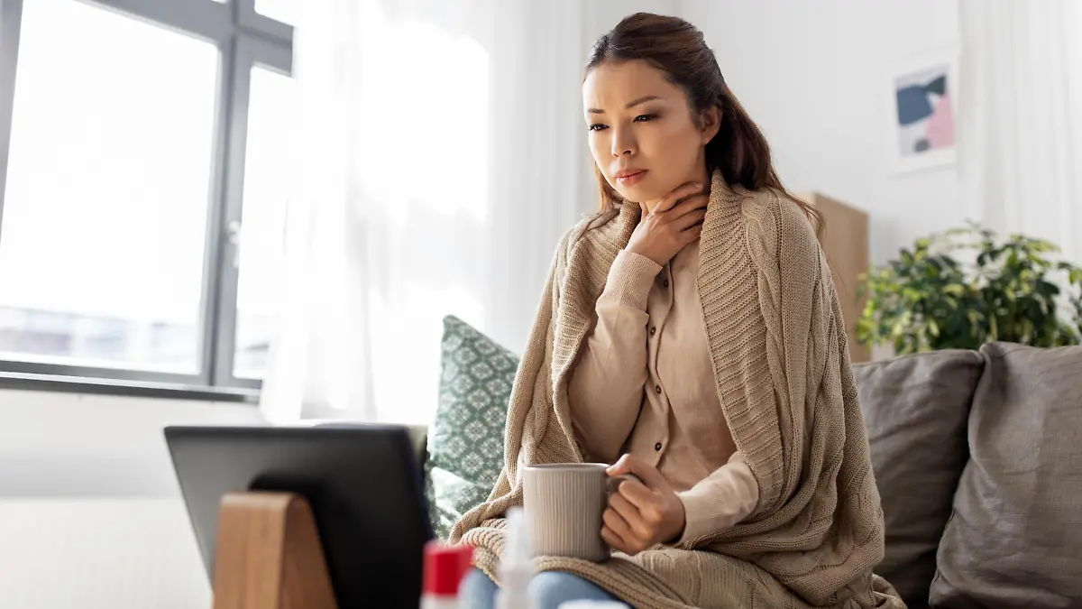 medicine, healthcare and technology concept - sick young asian woman having video call or online consultation on tablet pc computer and drinking tea at home