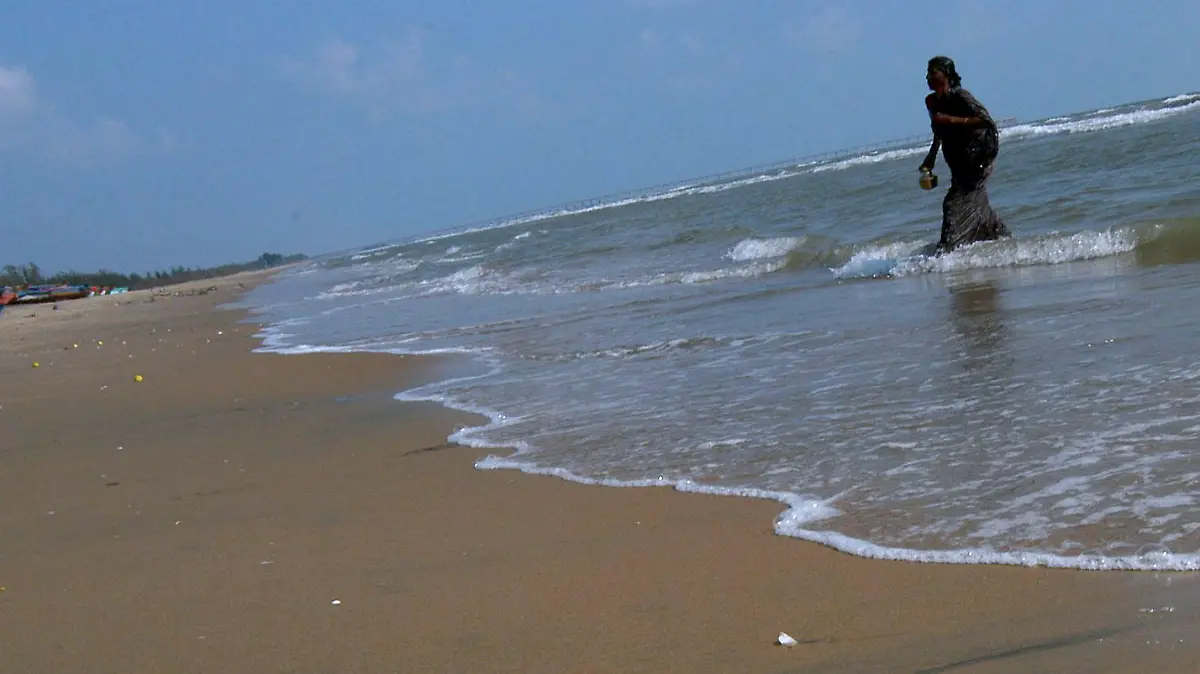 A flower garland used in a Hindu death ceremony for a Tsunami victim lies on the sandy beach after it was left into the sea along with other offerings by a family member (seen in the background), at the Samanthanpettai coast, Serathur village in Nagapattinam District in Tamil Nadu, India, on the early hours of Monday, 26 December 2005. Across India's southern coast and its Andaman and Nicobar islands, survivors of last year's tsunami remembered their dead on Monday with prayers, candlelight vigils and unveiling of memorials. EPA/MANJUNATH KIRAN +++(c) dpa - Bildfunk+++
