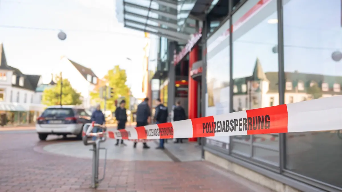 19.10.2022, Schleswig-Holstein, Schleswig: Eine Sparkassenfiliale ist mit Flatterband abgesprerrt. In einer Sparkassenfiliale in Schleswig sind am Mittwoch zwei tote Menschen gefunden worden. Hintergründe seien noch unbekannt, die Ermittlungen liefen zur Stunde noch, sagte ein Polizeisprecher am Vormittag. Bisher gebe es keinerlei Anhaltspunkte, die für oder gegen ein Tötungsdelikt sprächen. Foto: Benjamin Nolte/dpa +++ dpa-Bildfunk +++